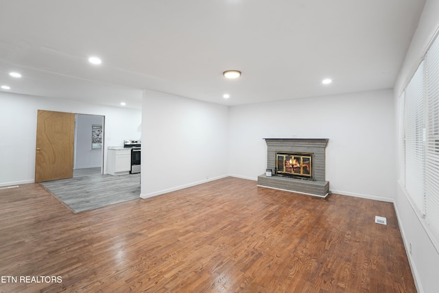 unfurnished living room with a brick fireplace and hardwood / wood-style flooring