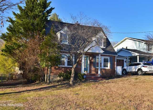 new england style home featuring a garage and a front yard