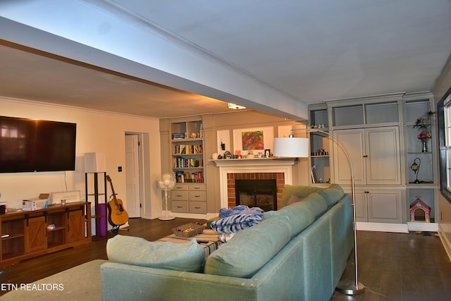 living room with a brick fireplace, built in shelves, dark hardwood / wood-style flooring, and crown molding