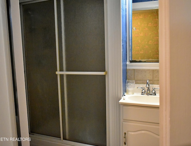 bathroom featuring tasteful backsplash, a shower with shower door, and vanity