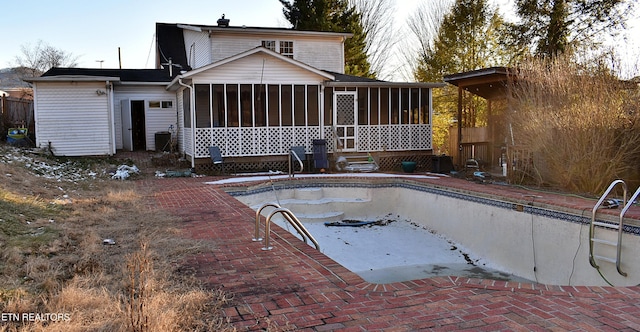 back of house featuring a sunroom, a patio, and an empty pool