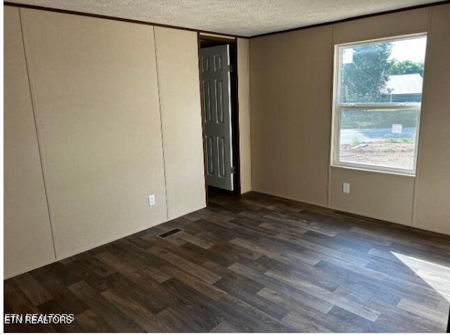 spare room featuring dark hardwood / wood-style flooring and a textured ceiling