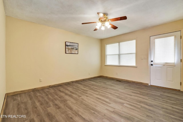 empty room with hardwood / wood-style flooring, a textured ceiling, and ceiling fan