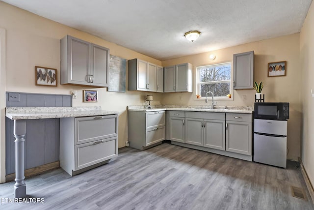 kitchen featuring gray cabinets, sink, hardwood / wood-style floors, and stainless steel refrigerator