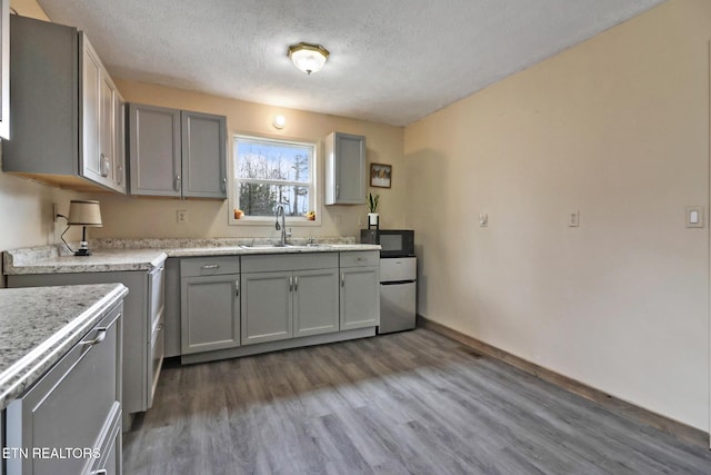 kitchen with dark wood-type flooring, sink, gray cabinetry, a textured ceiling, and stainless steel refrigerator
