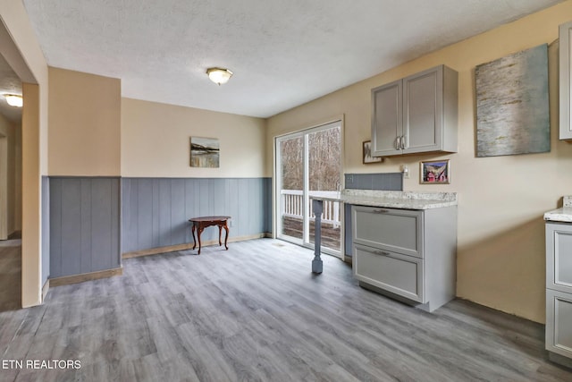 kitchen featuring gray cabinets, a textured ceiling, and light wood-type flooring
