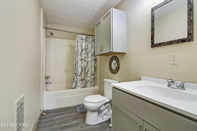 full bathroom featuring shower / tub combo, hardwood / wood-style floors, vanity, a textured ceiling, and toilet