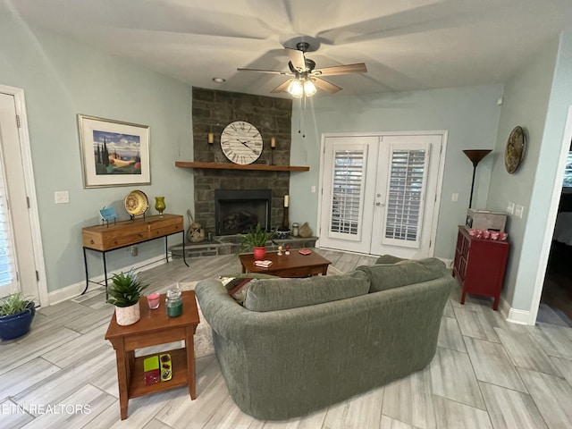 living room with ceiling fan, plenty of natural light, french doors, and a stone fireplace