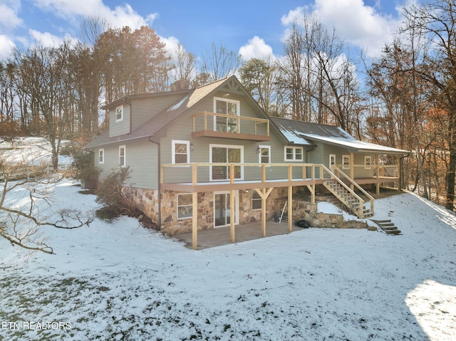 snow covered rear of property with a deck