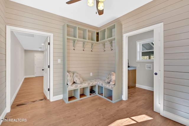 mudroom featuring ceiling fan, wood-type flooring, and wooden walls