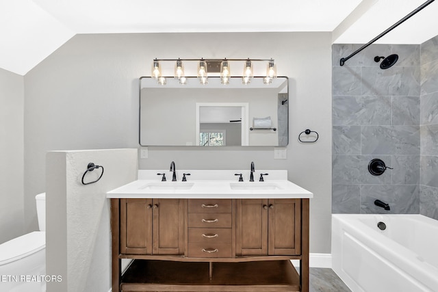 full bathroom featuring toilet, vanity, lofted ceiling, and tiled shower / bath