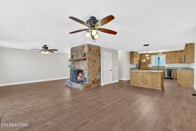 kitchen featuring dishwasher, a kitchen island, decorative light fixtures, dark hardwood / wood-style flooring, and a stone fireplace