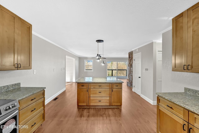 kitchen featuring light wood-type flooring, light stone countertops, ornamental molding, and pendant lighting