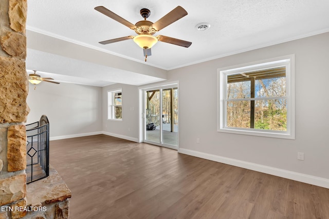 unfurnished living room featuring a textured ceiling, dark hardwood / wood-style flooring, a fireplace, ceiling fan, and crown molding