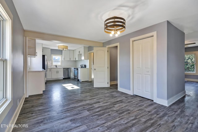 kitchen featuring dark wood-type flooring, white cabinetry, appliances with stainless steel finishes, and decorative backsplash