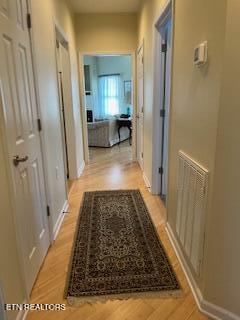 corridor with light wood finished floors and baseboards