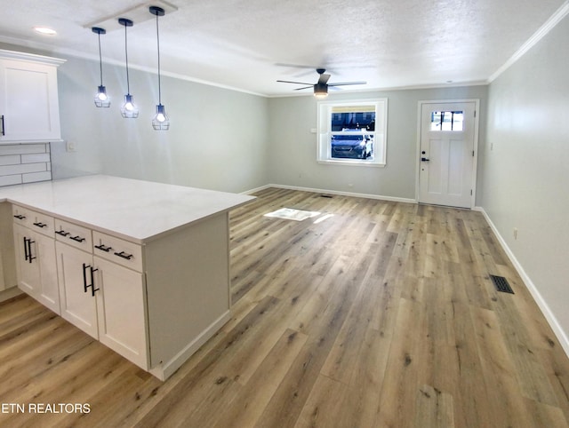 kitchen with kitchen peninsula, light wood-type flooring, hanging light fixtures, and white cabinets