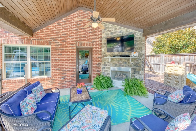 view of patio / terrace with ceiling fan and an outdoor living space with a fireplace