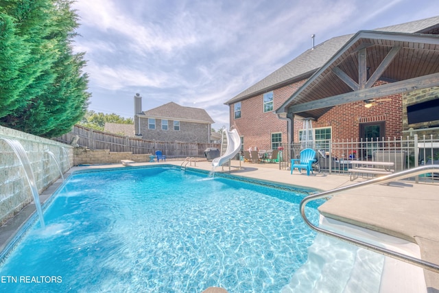 view of swimming pool with a patio, a water slide, and pool water feature