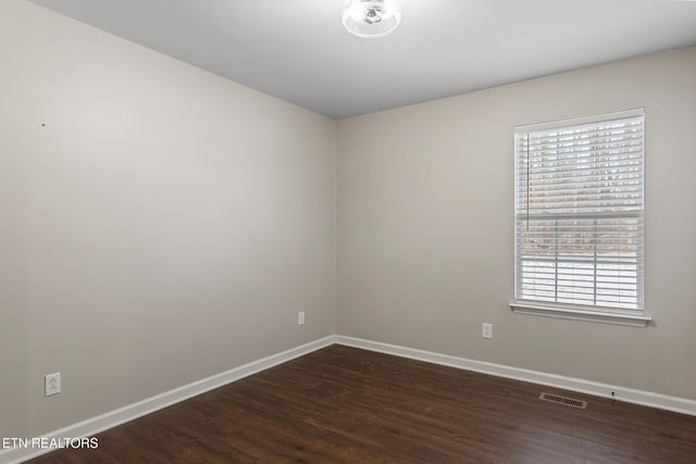 spare room with plenty of natural light and dark wood-type flooring