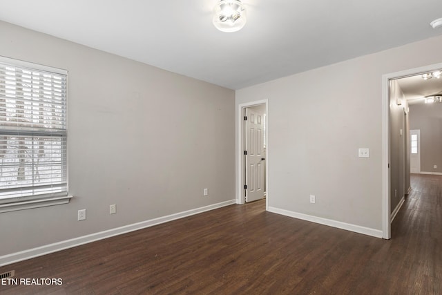 unfurnished room with plenty of natural light and dark wood-type flooring