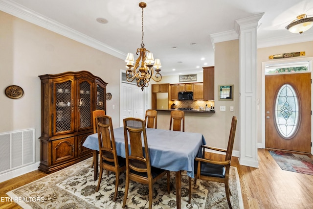 dining area featuring decorative columns, light hardwood / wood-style flooring, ornamental molding, and a chandelier