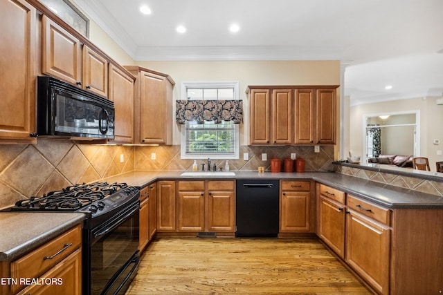 kitchen with black appliances, light hardwood / wood-style flooring, ornamental molding, and sink