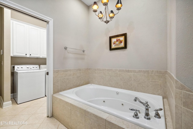 bathroom with a relaxing tiled tub, an inviting chandelier, separate washer and dryer, and tile patterned flooring