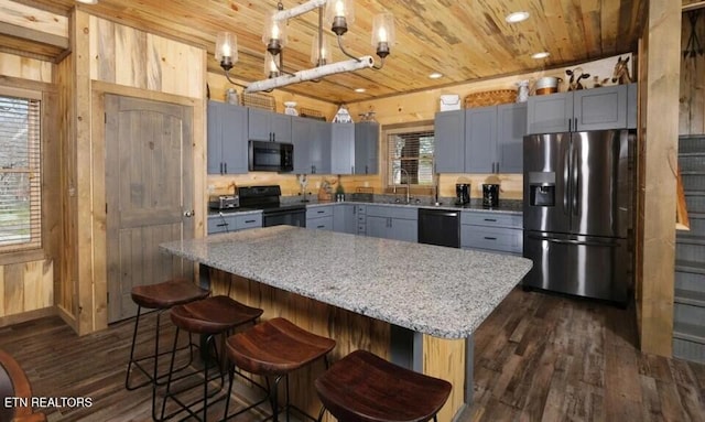 kitchen featuring black appliances, wood ceiling, a kitchen island, dark wood-type flooring, and wooden walls