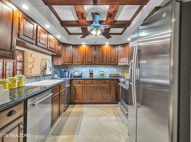 kitchen with sink, ceiling fan, dark stone countertops, beam ceiling, and stainless steel appliances