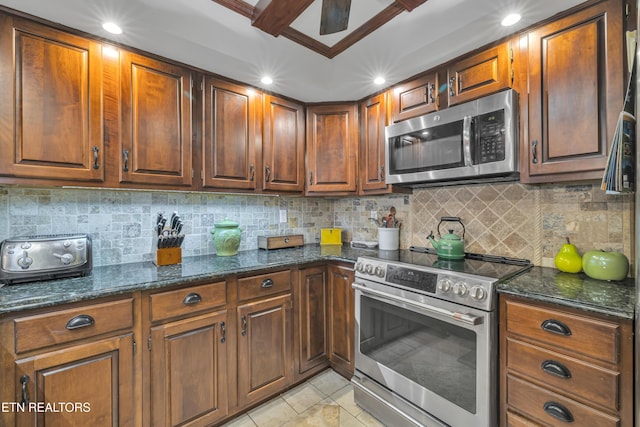 kitchen with dark stone countertops, appliances with stainless steel finishes, light tile patterned floors, and backsplash