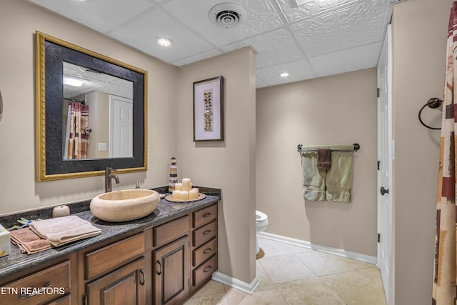 bathroom featuring vanity, a paneled ceiling, tile patterned floors, and toilet