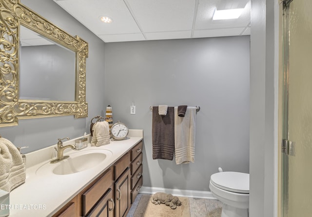 bathroom featuring tile patterned flooring, vanity, a paneled ceiling, and toilet