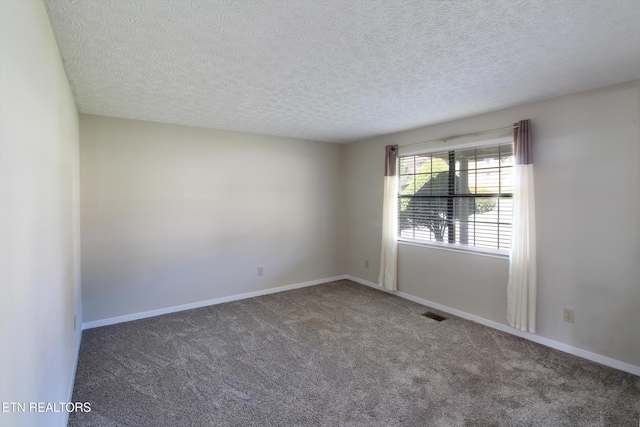 spare room with dark colored carpet, visible vents, a textured ceiling, and baseboards