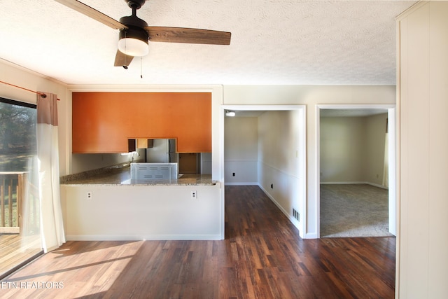 kitchen with dark wood-style flooring, ceiling fan, a textured ceiling, and baseboards