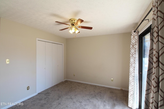 unfurnished bedroom featuring a closet, carpet flooring, a textured ceiling, and baseboards