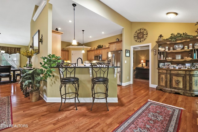 56 Westridge Ct, Fairfield Glade, TN 38558 - kitchen featuring appliances with stainless steel finishes, a peninsula, a breakfast bar, and wood finished floors