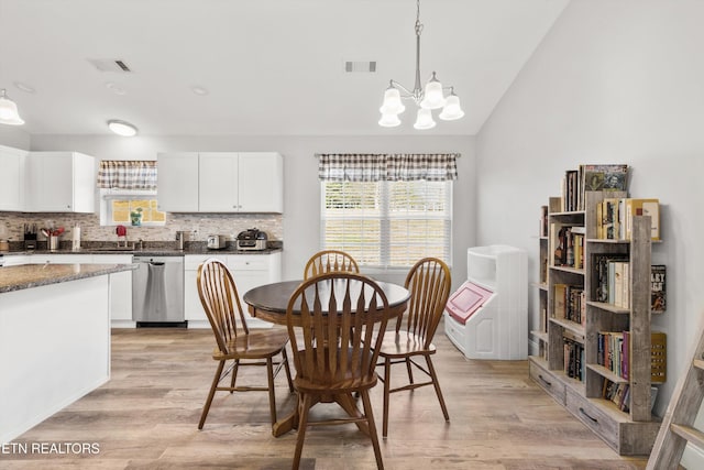 dining space featuring lofted ceiling, a notable chandelier, and light wood-type flooring