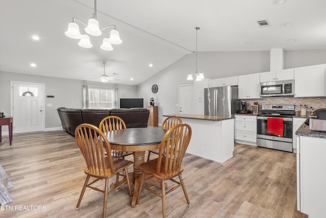 dining space featuring vaulted ceiling with beams, ceiling fan with notable chandelier, and light hardwood / wood-style floors