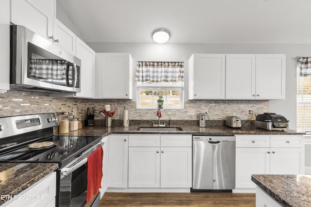 kitchen featuring sink, white cabinets, stainless steel appliances, and dark stone countertops