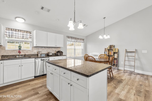 kitchen featuring a kitchen island, stainless steel dishwasher, sink, hanging light fixtures, and white cabinets