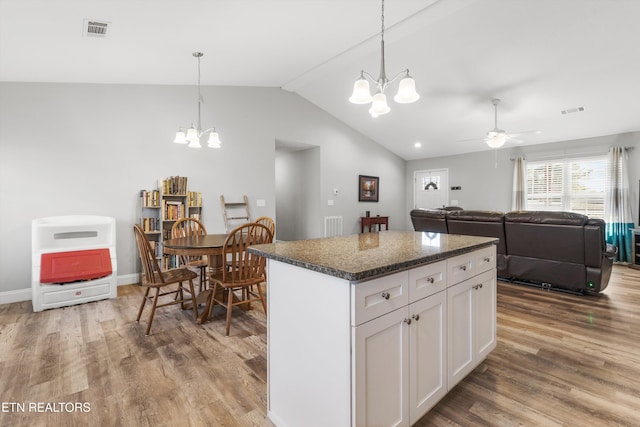 kitchen featuring decorative light fixtures, vaulted ceiling with beams, wood-type flooring, a kitchen island, and white cabinets