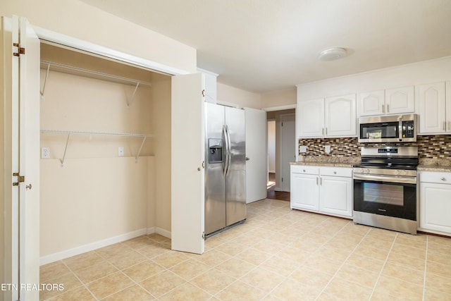 kitchen with white cabinets, stainless steel appliances, decorative backsplash, and light tile patterned flooring