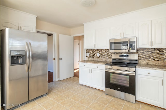 kitchen featuring white cabinets, stainless steel appliances, light tile patterned floors, and decorative backsplash