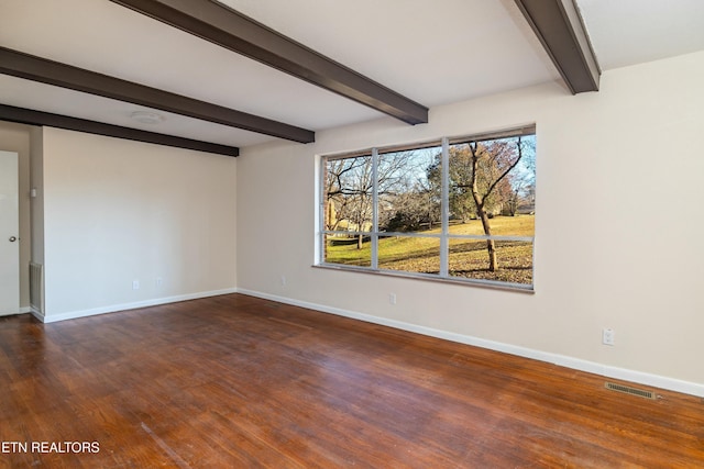 spare room featuring dark wood-type flooring and beamed ceiling