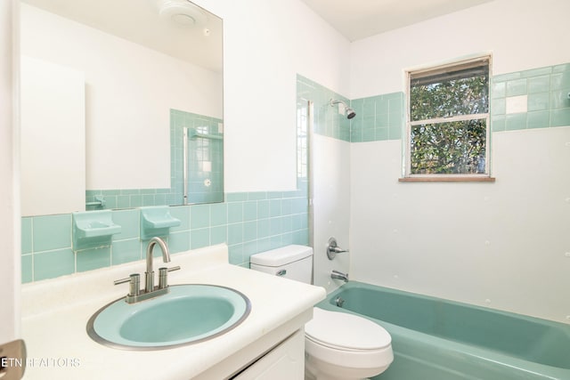 full bathroom with tile walls, tiled shower / bath combo, vanity, and toilet