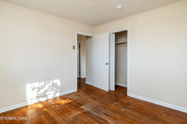 unfurnished bedroom with dark hardwood / wood-style flooring and a closet