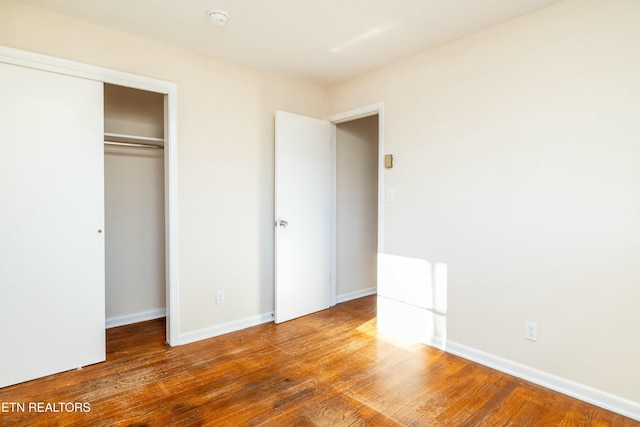 unfurnished bedroom featuring a closet and hardwood / wood-style floors