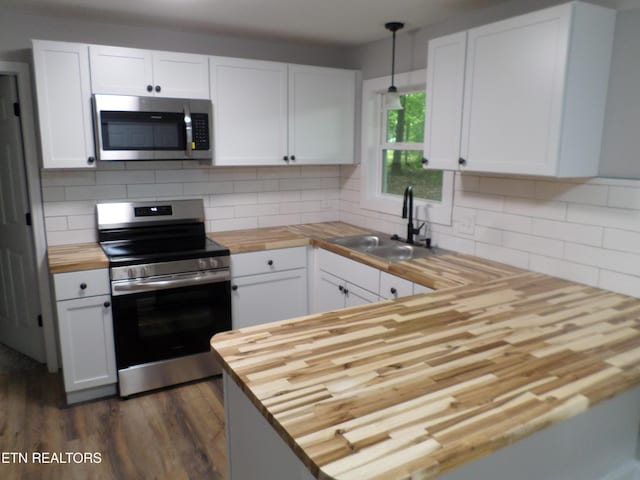 kitchen featuring pendant lighting, white cabinets, stainless steel appliances, and wooden counters