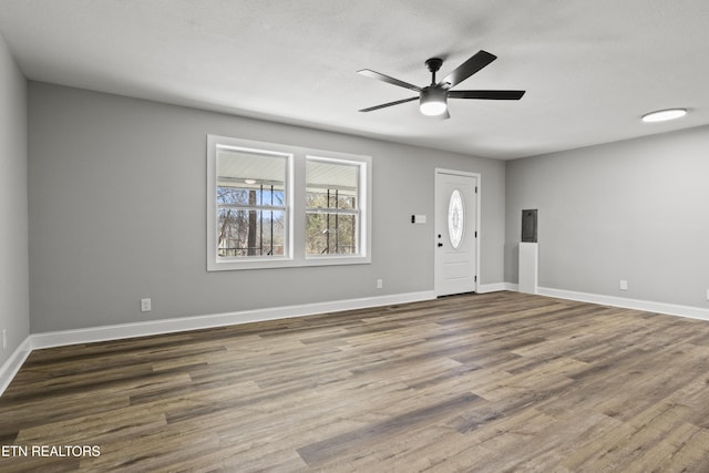 foyer entrance featuring a textured ceiling, wood finished floors, a ceiling fan, and baseboards